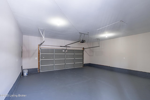 garage featuring a garage door opener, electric panel, and baseboards