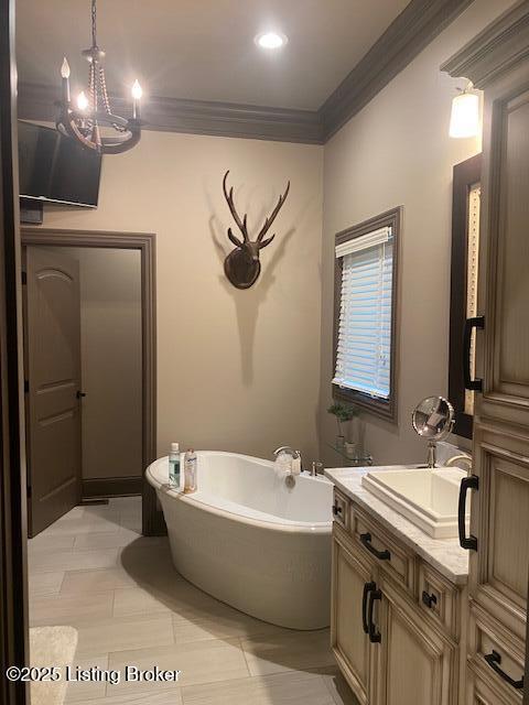 full bath with a freestanding tub, ornamental molding, and vanity