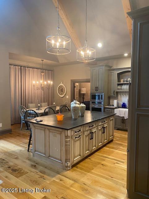 kitchen featuring a breakfast bar, dark countertops, appliances with stainless steel finishes, a kitchen island, and a chandelier