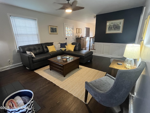 living area featuring dark wood-type flooring, wainscoting, and a ceiling fan