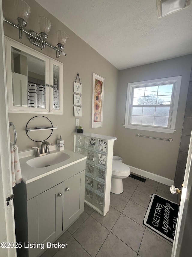 bathroom featuring a textured ceiling, toilet, vanity, baseboards, and tile patterned floors