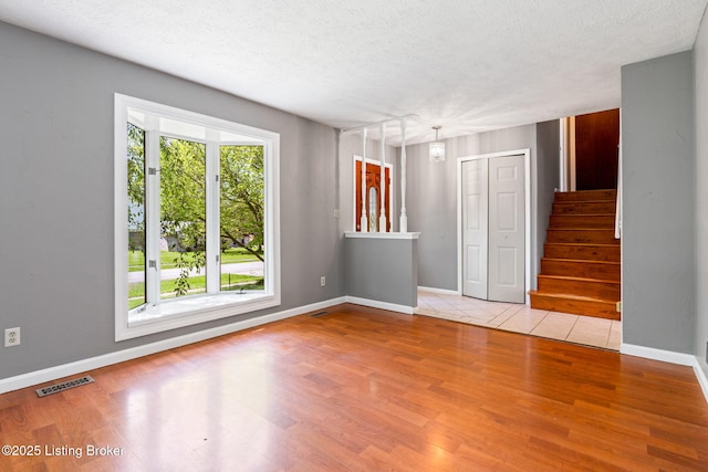 10207 El Coco Ct, Louisville, KY 40291 - unfurnished living room with wood finished floors, stairs, and a textured ceiling