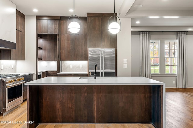 kitchen with hanging light fixtures, modern cabinets, high end appliances, and light countertops