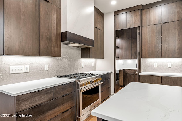 kitchen featuring premium range hood, dark brown cabinets, high end stainless steel range, decorative backsplash, and modern cabinets