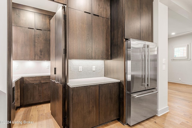 kitchen featuring freestanding refrigerator, light countertops, dark brown cabinets, and modern cabinets