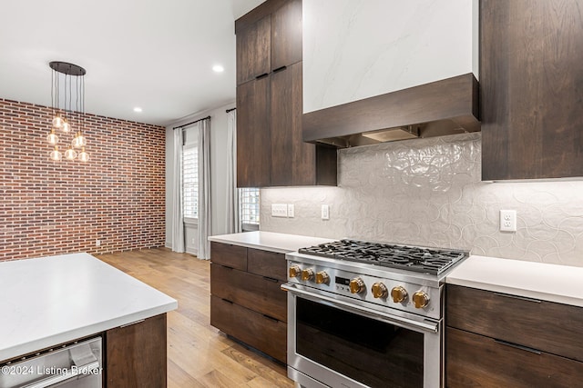 kitchen featuring brick wall, light countertops, high end stainless steel range, modern cabinets, and pendant lighting