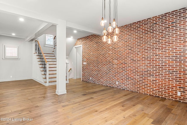 unfurnished dining area featuring recessed lighting, light wood-style flooring, brick wall, and stairs