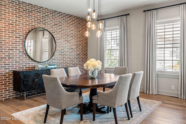 dining area with light wood-style floors, brick wall, visible vents, and baseboards