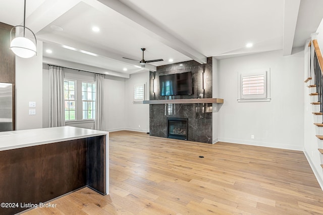 kitchen with open floor plan, beamed ceiling, decorative light fixtures, light countertops, and a high end fireplace