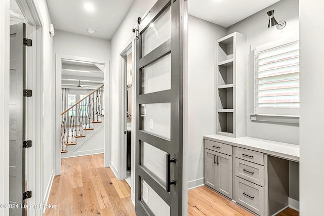 interior space with light wood-style floors, baseboards, and a barn door