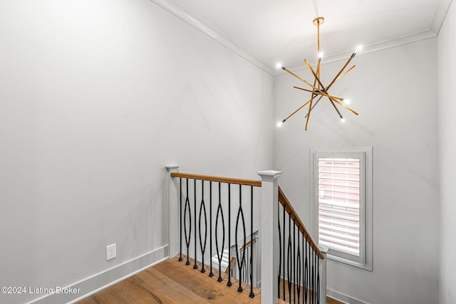 stairs with baseboards, a chandelier, crown molding, and wood finished floors