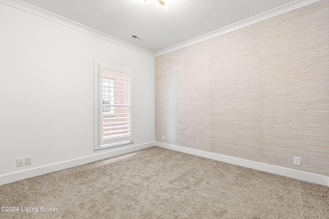 spare room featuring carpet floors, visible vents, ornamental molding, and baseboards