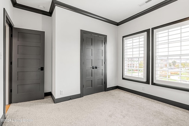 unfurnished bedroom featuring a closet, visible vents, ornamental molding, carpet flooring, and baseboards