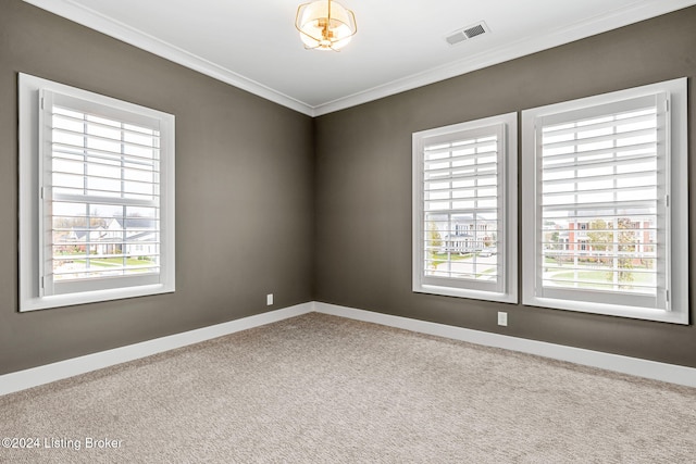 carpeted spare room with ornamental molding, visible vents, and baseboards