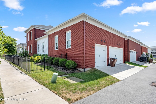 view of side of home featuring a yard, fence, concrete driveway, and brick siding