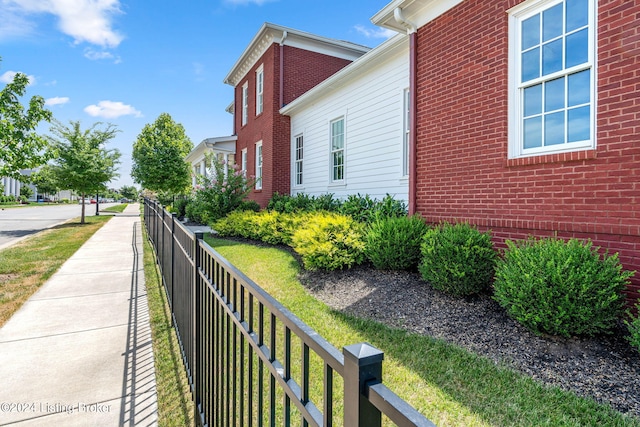 view of property exterior featuring brick siding and fence