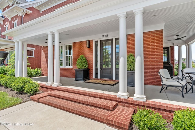 doorway to property with ceiling fan, a porch, and brick siding