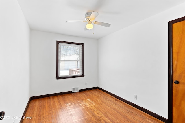 unfurnished room with a ceiling fan, wood finished floors, visible vents, and baseboards