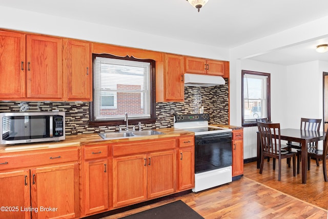 kitchen with white range with electric cooktop, stainless steel microwave, light countertops, under cabinet range hood, and a sink