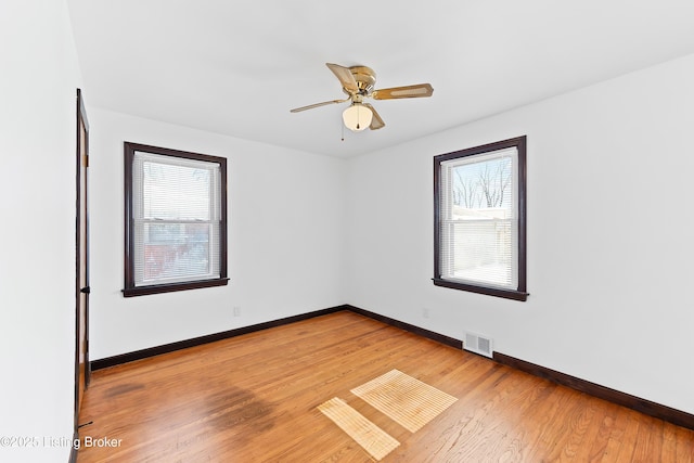 spare room featuring light wood-type flooring, plenty of natural light, and visible vents