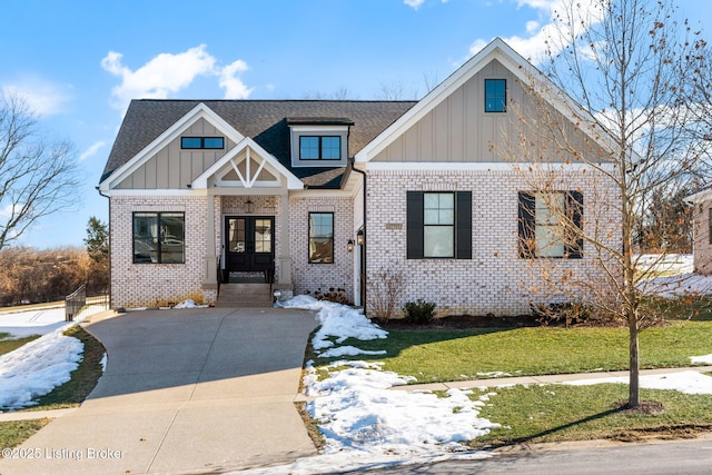 view of front of home with board and batten siding, french doors, brick siding, and a front lawn