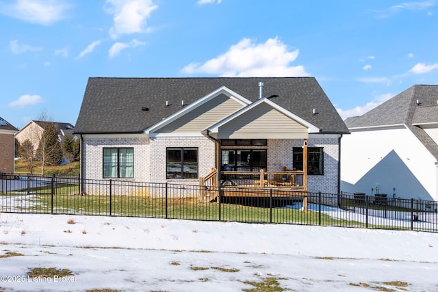 bungalow-style house with a fenced front yard, a shingled roof, a lawn, and brick siding