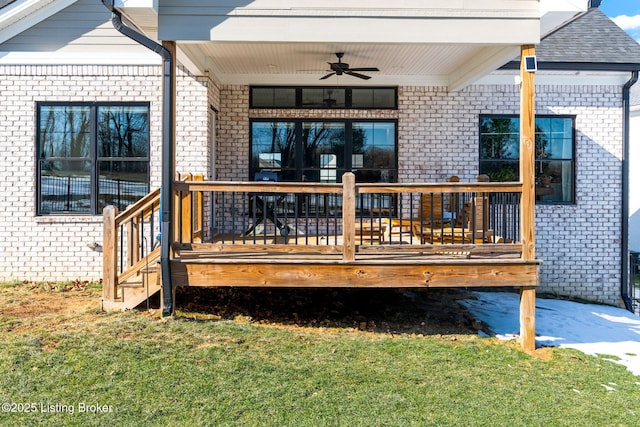 entrance to property with a yard, brick siding, and a ceiling fan