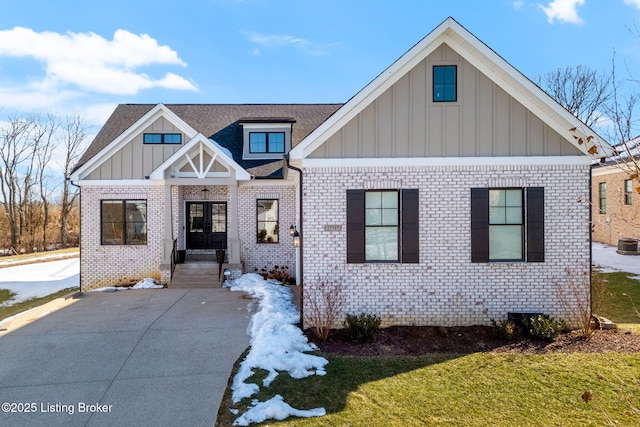 view of front facade featuring a shingled roof, board and batten siding, and brick siding