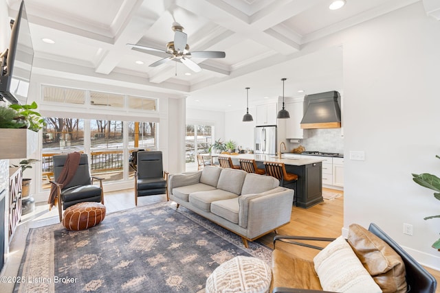 living area with beam ceiling, recessed lighting, light wood-style floors, ornamental molding, and coffered ceiling