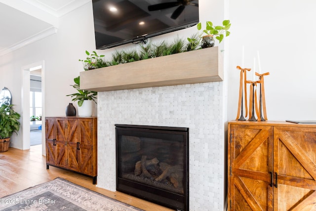 interior details featuring a brick fireplace, crown molding, and wood finished floors