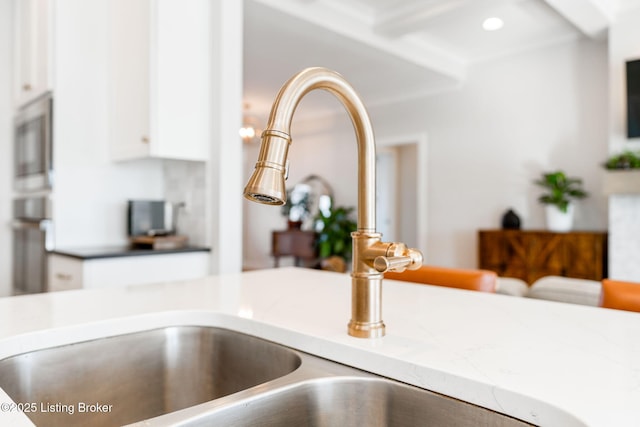 interior details with white cabinets, a sink, and recessed lighting