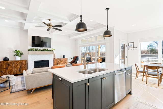 kitchen with a sink, light countertops, gray cabinets, an island with sink, and decorative light fixtures