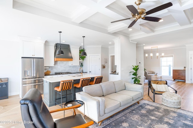 living room with beam ceiling, coffered ceiling, crown molding, and light wood-style flooring