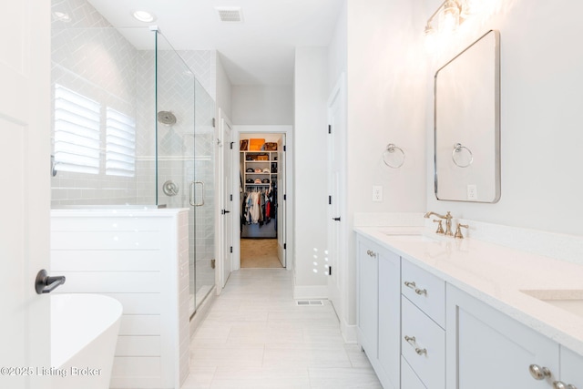 bathroom with a sink, visible vents, a shower stall, double vanity, and a walk in closet