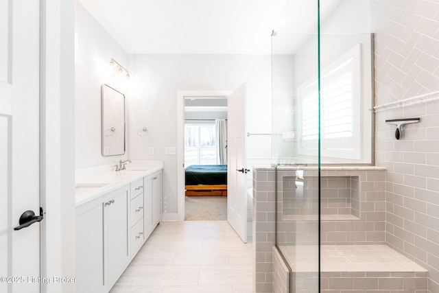 full bath featuring a sink, double vanity, tiled shower, and ensuite bath