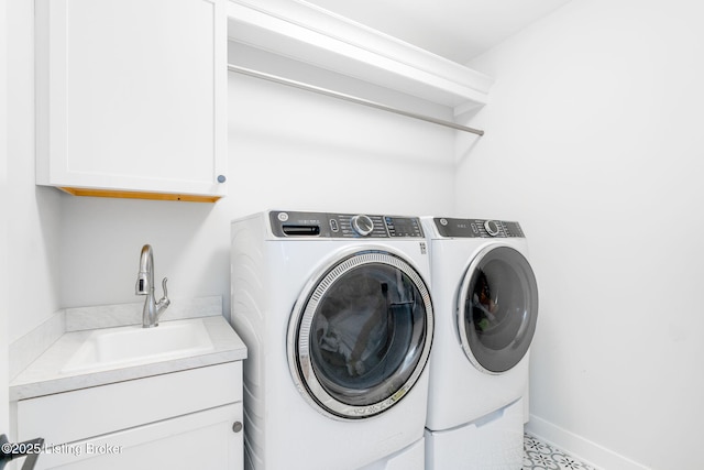 washroom with cabinet space, baseboards, washer and dryer, and a sink