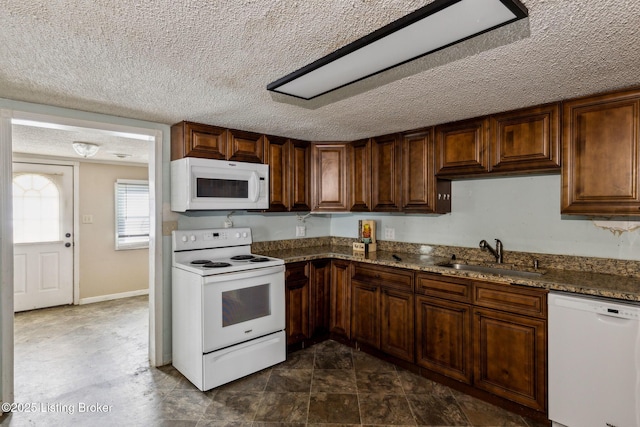 kitchen featuring white appliances, stone countertops, a textured ceiling, and a sink