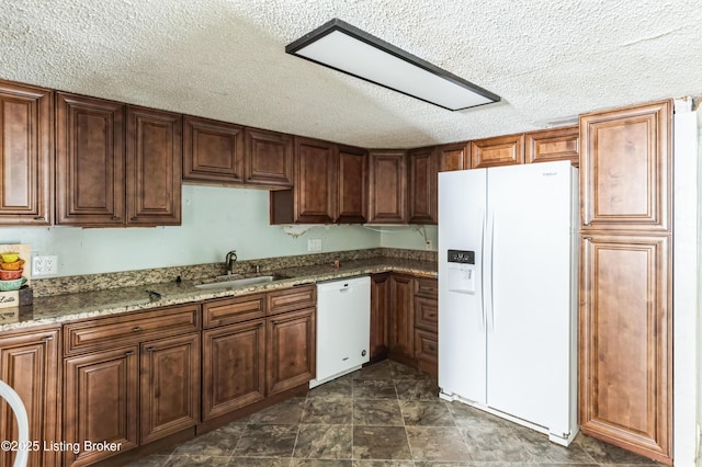 kitchen with white appliances, a sink, a textured ceiling, and light stone countertops