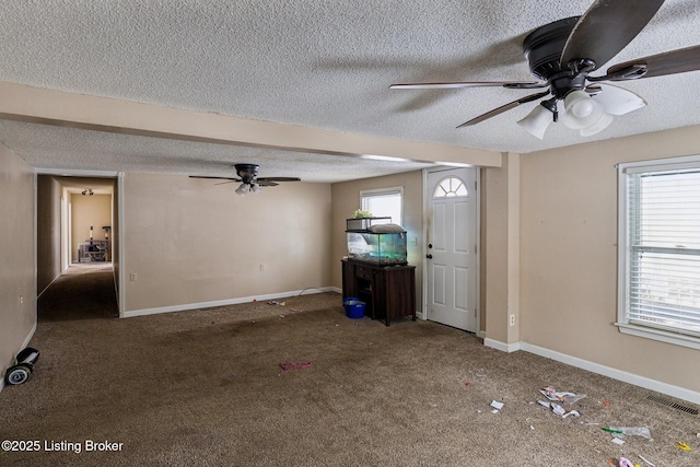 unfurnished living room featuring a textured ceiling, visible vents, a wealth of natural light, and carpet flooring