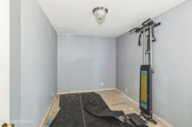 unfurnished room with a textured ceiling and baseboards