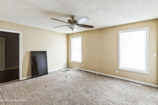 unfurnished room featuring a textured ceiling, carpet flooring, a ceiling fan, visible vents, and baseboards