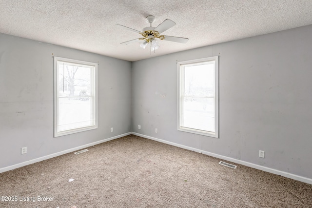 spare room featuring carpet floors, visible vents, and a healthy amount of sunlight