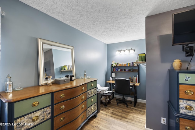 office area featuring a textured ceiling, light wood finished floors, and baseboards