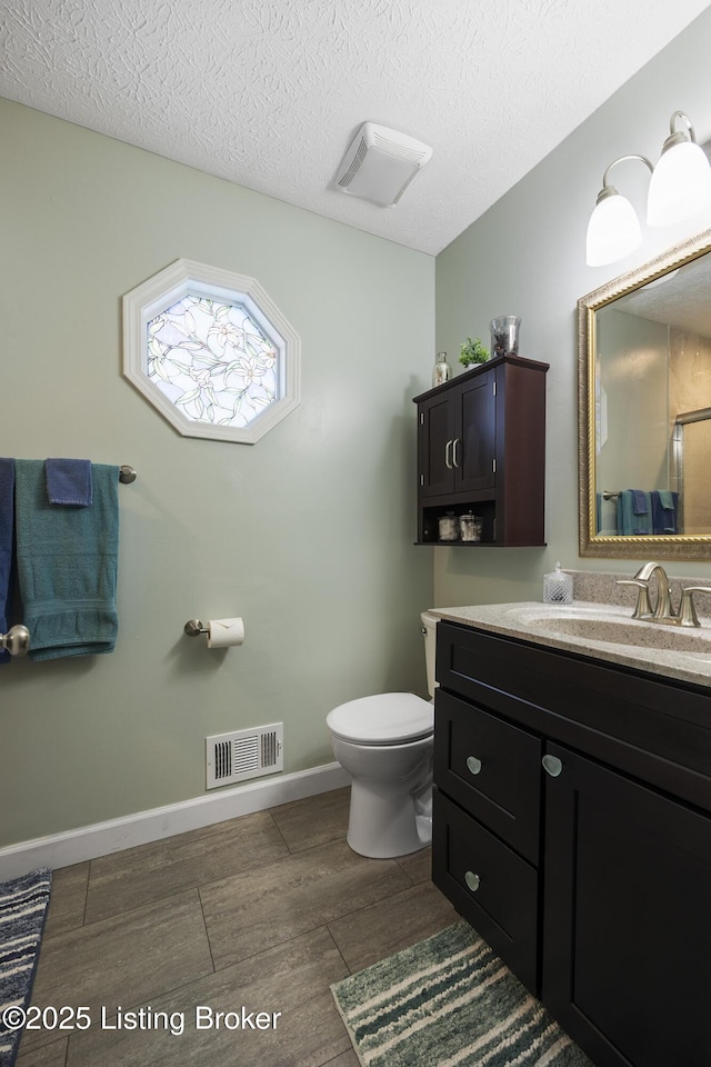 full bathroom with visible vents, a shower with shower door, vanity, a textured ceiling, and wood finished floors