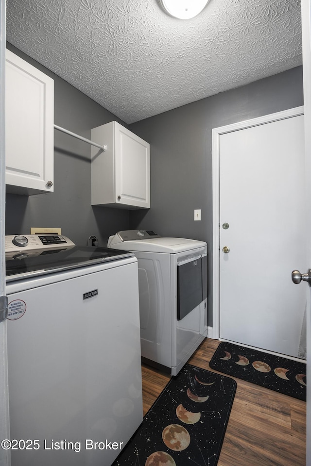 clothes washing area with dark wood-style floors, a textured ceiling, cabinet space, and washer and dryer