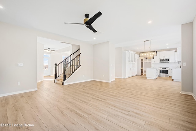 unfurnished living room with recessed lighting, stairway, a ceiling fan, light wood-type flooring, and baseboards