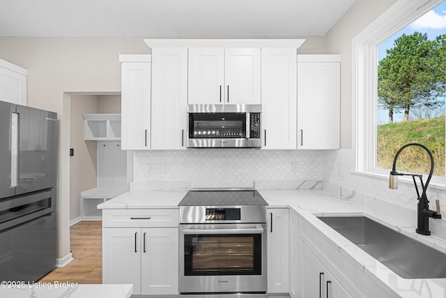 kitchen with stainless steel appliances, a sink, and white cabinets