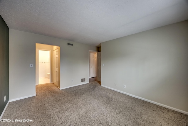 empty room featuring baseboards, visible vents, a textured ceiling, and carpet flooring