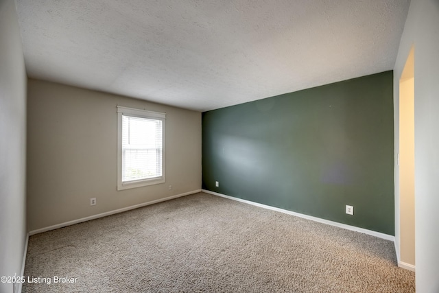 carpeted spare room with baseboards and a textured ceiling