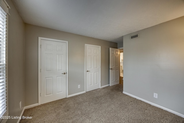 unfurnished bedroom featuring carpet floors, visible vents, and baseboards